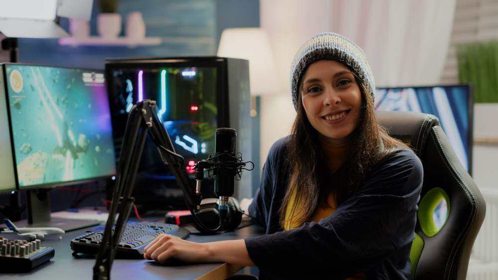 Free photo portrait of woman streamer looking at camera after playing space shooter games using professional rgb keypad on powerful computer. pro player streaming online videogames in gaming home studio